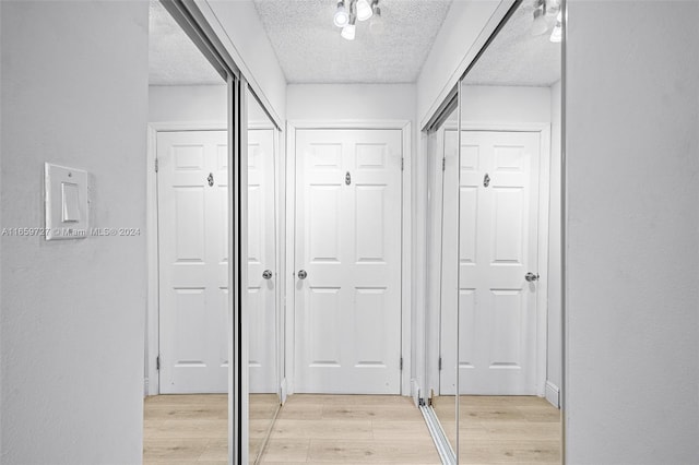 hall with a textured ceiling and light hardwood / wood-style floors