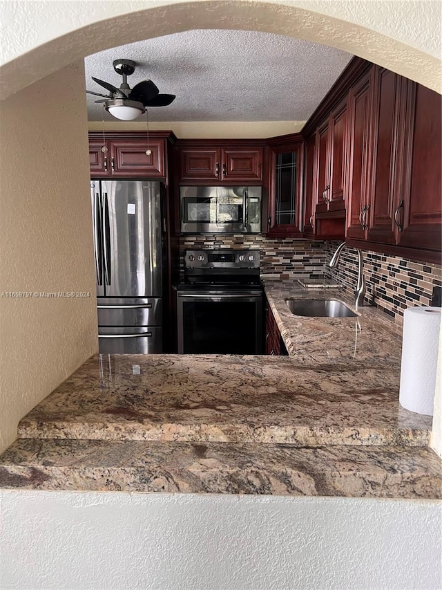 kitchen with a textured ceiling, sink, decorative backsplash, appliances with stainless steel finishes, and ceiling fan