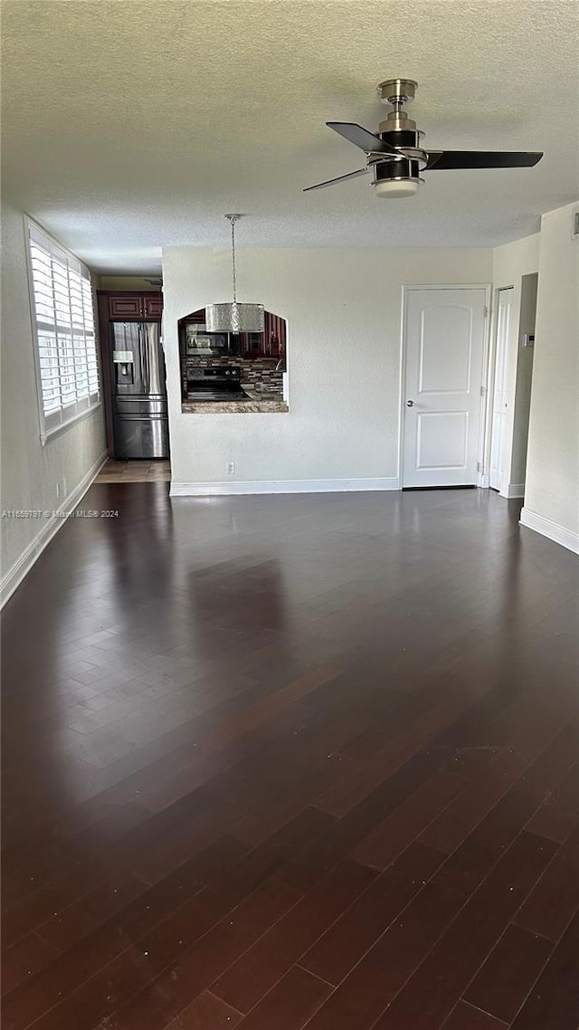 unfurnished living room featuring ceiling fan, dark hardwood / wood-style floors, and a textured ceiling