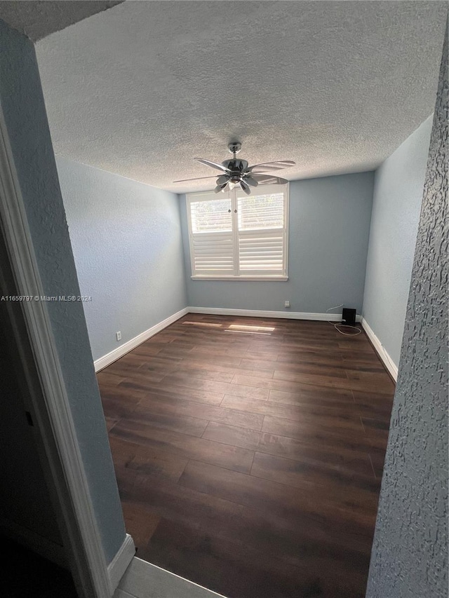 empty room featuring a textured ceiling, dark wood-type flooring, and ceiling fan