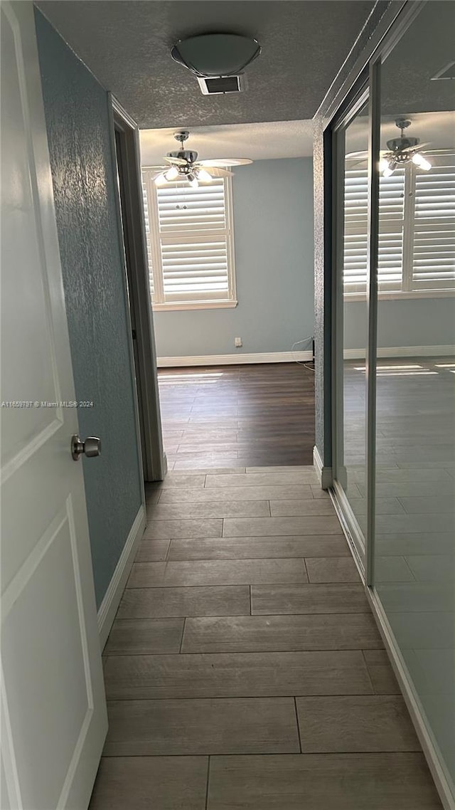 hall featuring a textured ceiling and hardwood / wood-style floors