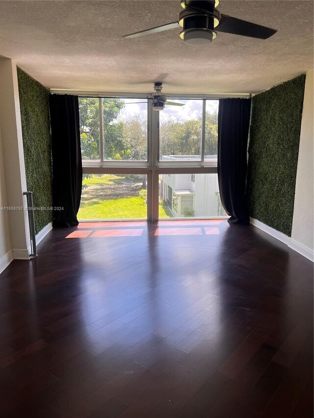 unfurnished room with a textured ceiling, dark hardwood / wood-style flooring, and ceiling fan