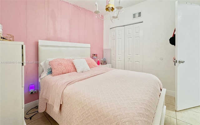 bedroom with an inviting chandelier, light tile patterned floors, and a closet