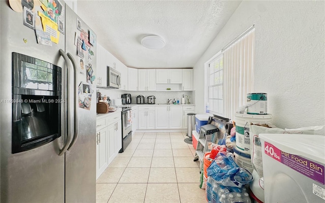 kitchen featuring stainless steel appliances, white cabinetry, a textured ceiling, and light tile patterned floors