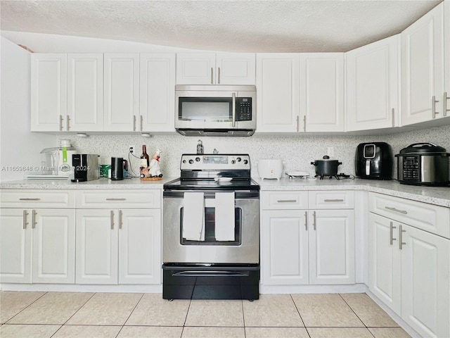 kitchen with appliances with stainless steel finishes, lofted ceiling, and white cabinetry