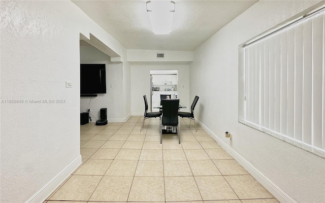 hallway featuring a textured ceiling and light tile patterned floors