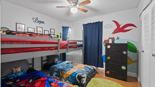 bedroom with ceiling fan, wood-type flooring, a textured ceiling, and a closet