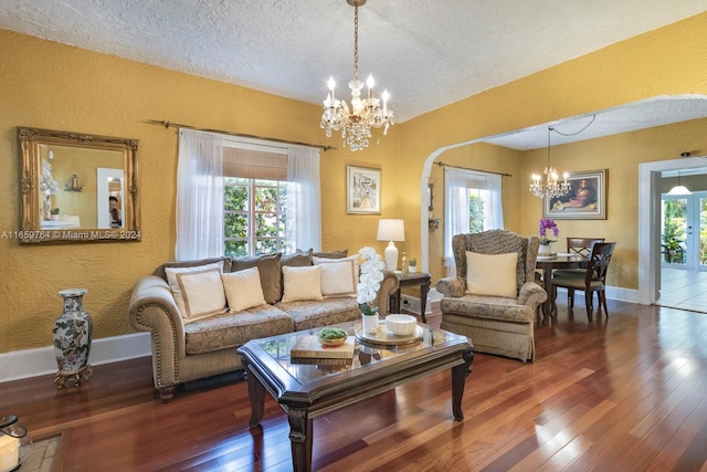 living room featuring dark hardwood / wood-style floors, a textured ceiling, a notable chandelier, and a healthy amount of sunlight