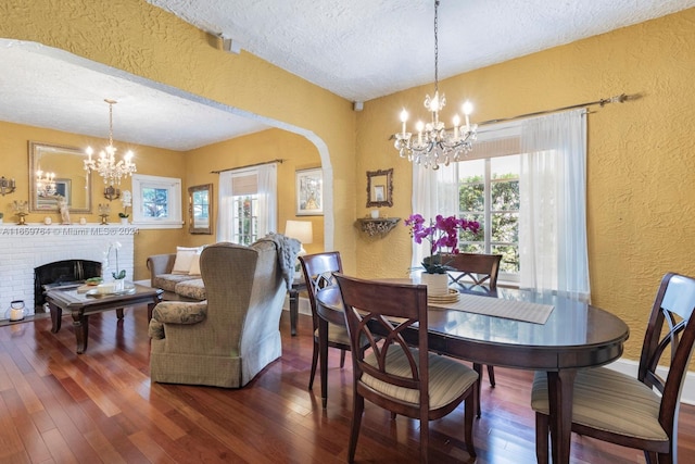 dining space with a fireplace, dark hardwood / wood-style flooring, plenty of natural light, and a textured ceiling