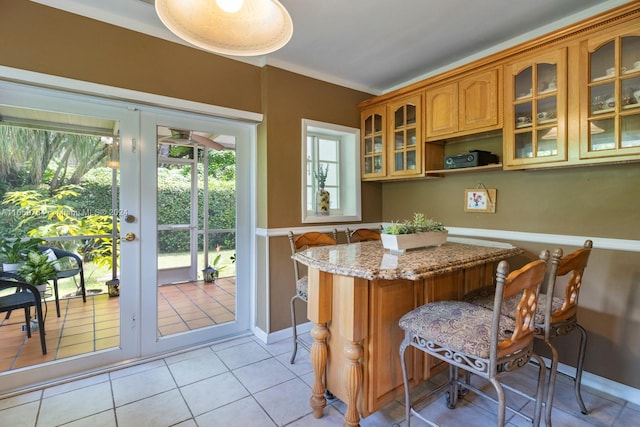 kitchen featuring a breakfast bar area, light stone counters, light tile patterned floors, and french doors