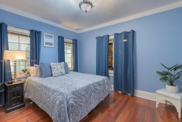 bedroom with ornamental molding and dark hardwood / wood-style floors