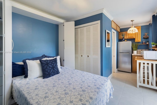 bedroom with a closet, light tile patterned floors, crown molding, and stainless steel refrigerator