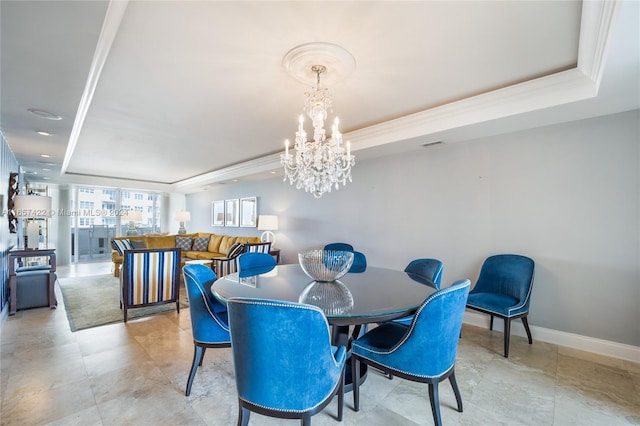 dining area featuring ornamental molding, an inviting chandelier, and a tray ceiling