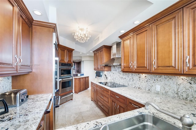 kitchen with tasteful backsplash, black electric stovetop, light stone countertops, and wall chimney range hood