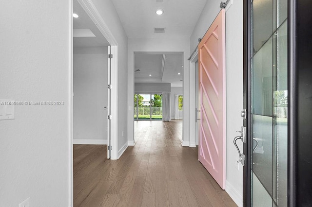 hall featuring a barn door and hardwood / wood-style flooring