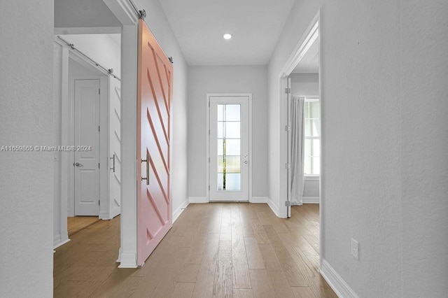 doorway with light wood-type flooring and a barn door