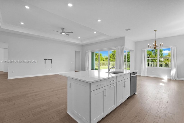 kitchen featuring ceiling fan with notable chandelier, a kitchen island with sink, sink, dishwasher, and white cabinets