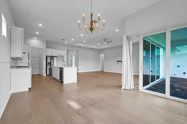 kitchen with white cabinetry, tasteful backsplash, an island with sink, decorative light fixtures, and appliances with stainless steel finishes