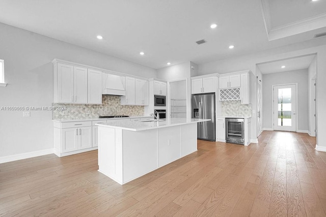 kitchen featuring built in microwave, wine cooler, stainless steel fridge with ice dispenser, an island with sink, and white cabinets