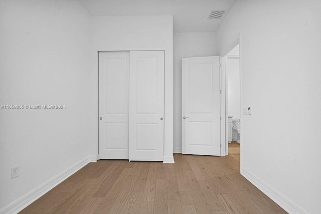 unfurnished bedroom with a closet and light wood-type flooring