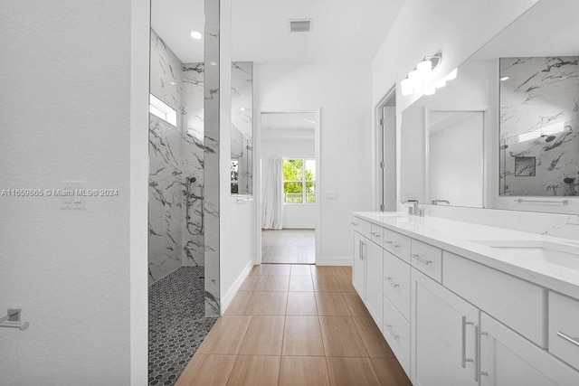 bathroom with a tile shower and vanity