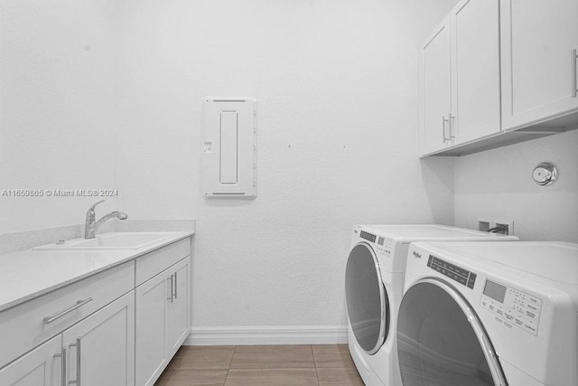 laundry area featuring cabinets, light tile patterned flooring, washing machine and dryer, and sink