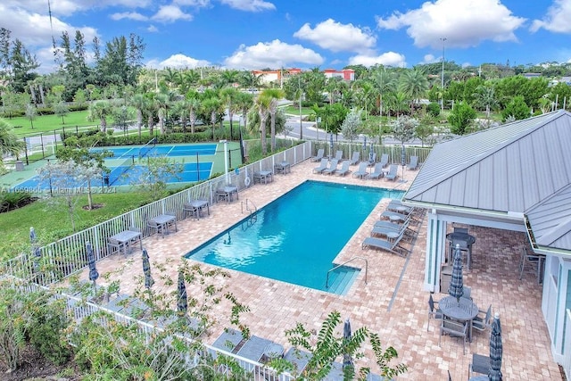 view of swimming pool with tennis court and a patio