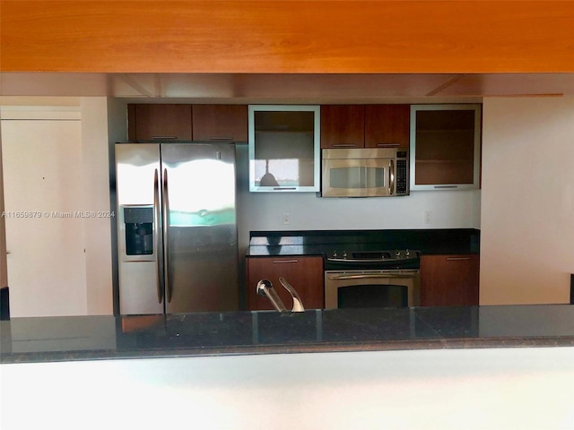 kitchen with sink, appliances with stainless steel finishes, and dark stone counters