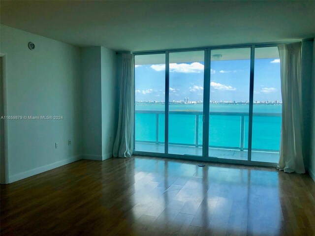 spare room with a water view, floor to ceiling windows, and wood-type flooring