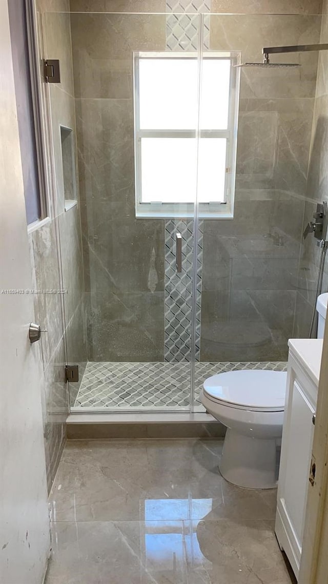 bathroom with tile walls, toilet, a shower with door, and vanity