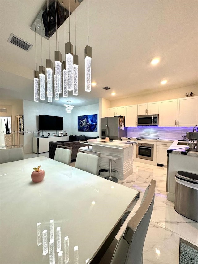 kitchen featuring pendant lighting, stainless steel appliances, and white cabinetry