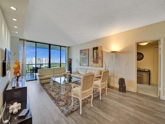 living room with a textured ceiling, a wall of windows, and hardwood / wood-style flooring