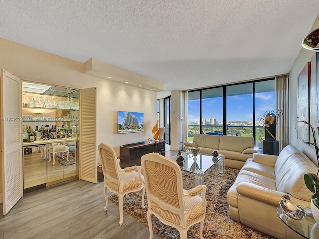 living room with a textured ceiling, light hardwood / wood-style flooring, bar, and expansive windows