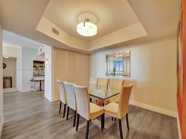 dining area with a raised ceiling and hardwood / wood-style flooring