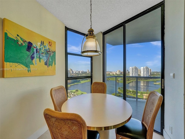 dining area featuring a textured ceiling, a water view, and a wall of windows