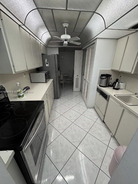 kitchen with white appliances, light tile patterned floors, sink, ceiling fan, and white cabinets