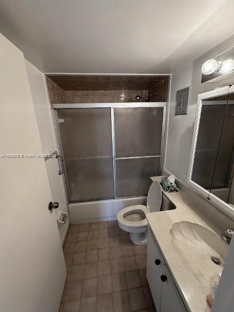 full bathroom featuring toilet, bath / shower combo with glass door, and vanity