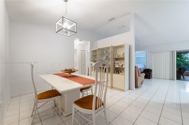 tiled dining room with a notable chandelier and vaulted ceiling