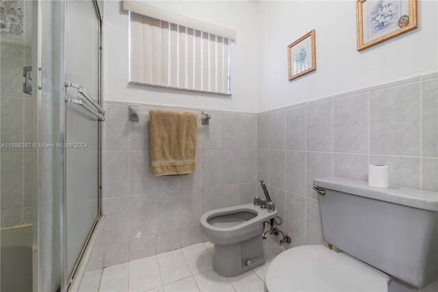 bathroom with tile walls, walk in shower, toilet, and a bidet