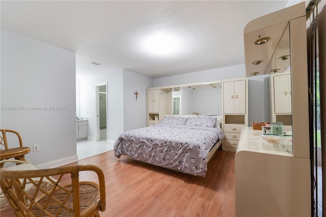 bedroom featuring a textured ceiling, hardwood / wood-style floors, and ensuite bathroom