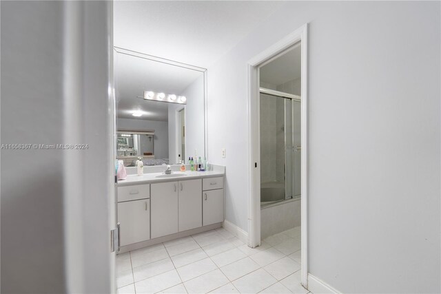 bathroom featuring vanity, tile patterned flooring, and enclosed tub / shower combo