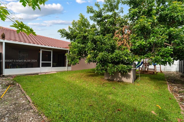 view of yard featuring a playground and a sunroom