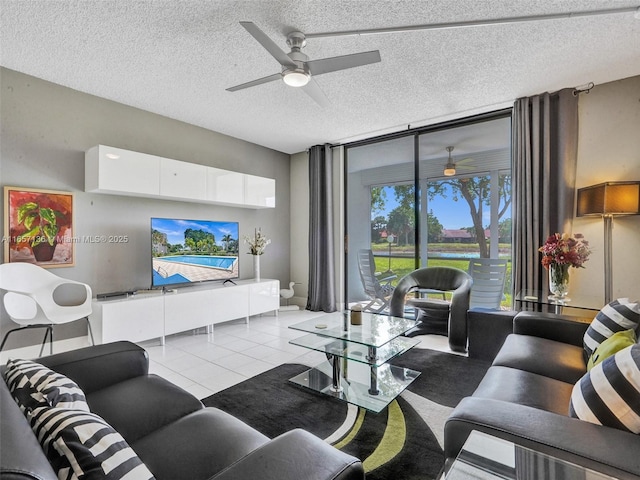 living room with ceiling fan, a textured ceiling, a wall of windows, and light tile patterned flooring