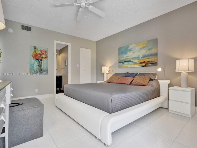 bedroom featuring light tile patterned flooring, ceiling fan, ensuite bathroom, and a textured ceiling