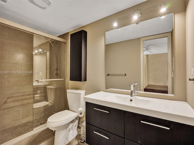 bathroom featuring toilet, vanity, ceiling fan, and a shower with door