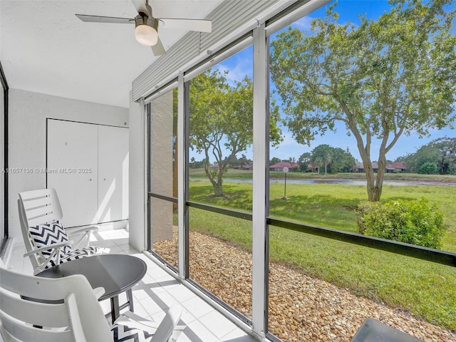 sunroom featuring ceiling fan and a water view