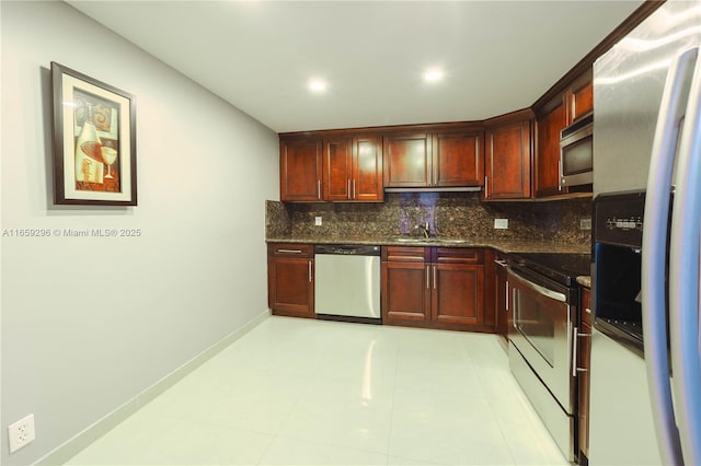 kitchen featuring appliances with stainless steel finishes, tasteful backsplash, sink, light tile patterned floors, and dark stone countertops