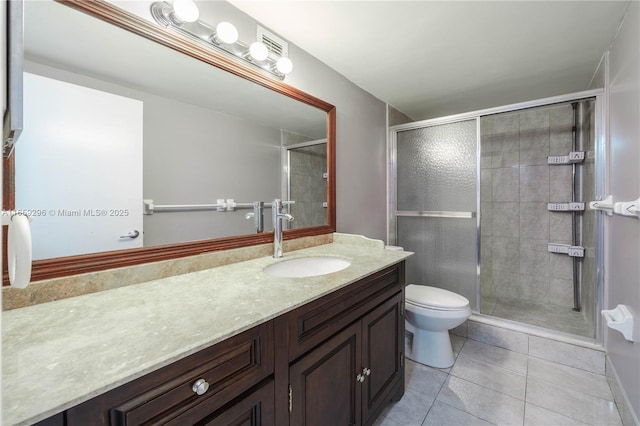 bathroom featuring toilet, vanity, tile patterned floors, and a shower with door