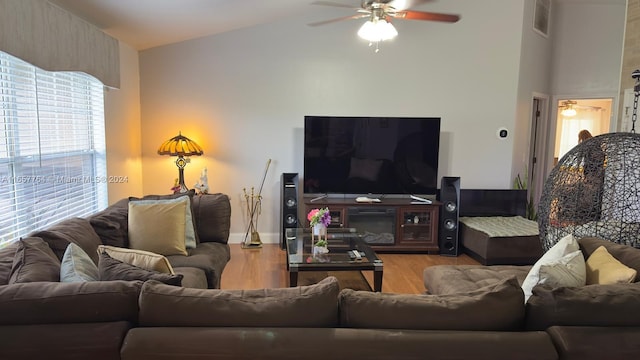 living room with a fireplace, vaulted ceiling, ceiling fan, and light hardwood / wood-style floors