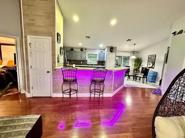 kitchen featuring dark hardwood / wood-style flooring, a breakfast bar area, backsplash, and lofted ceiling